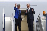Anthony Albanese and Penny Wong wave to the press pack before boarding plane