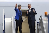 Anthony Albanese and Penny Wong wave to the press pack before boarding plane