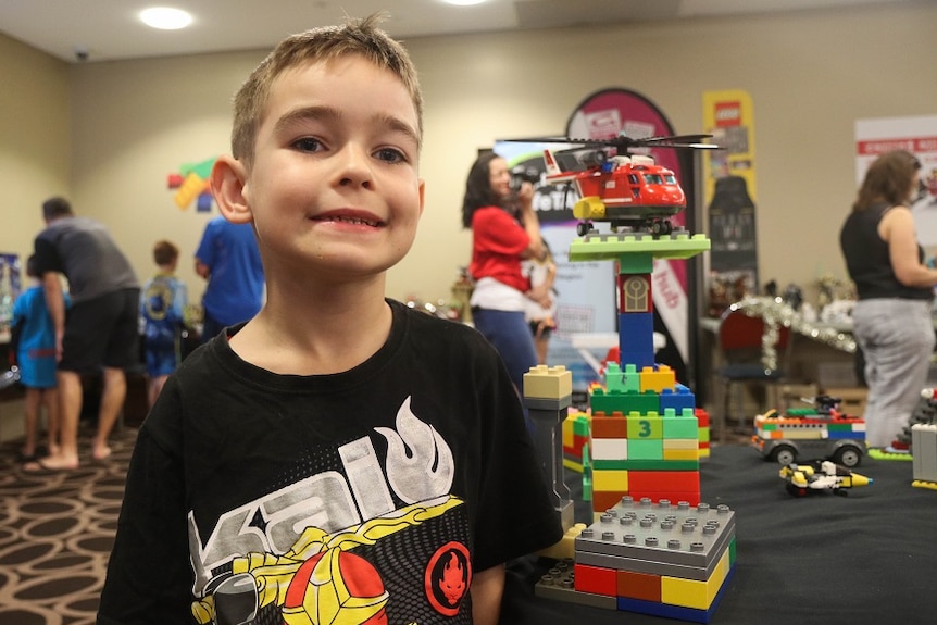 A young boy with a helicopter made with Lego.