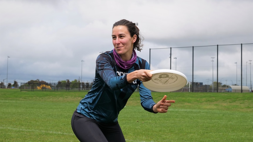 A woman holding a white frisbee prepares to throw it.