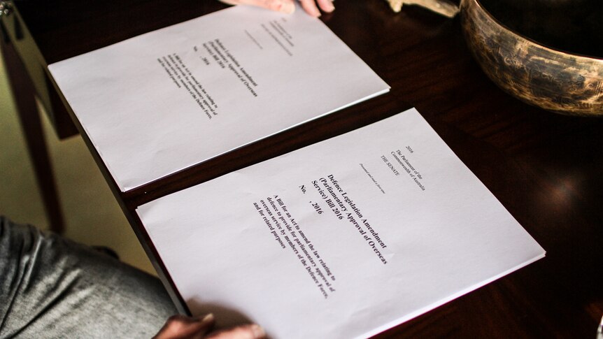 Two pieces of legislation on a desk with Mr Smith's hands on either side.