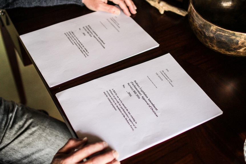 Two pieces of legislation on a desk with Mr Smith's hands on either side.