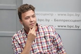 A waist-up photo of Jailed Belarus journalist Roman Protasevich takes part in a press conference.