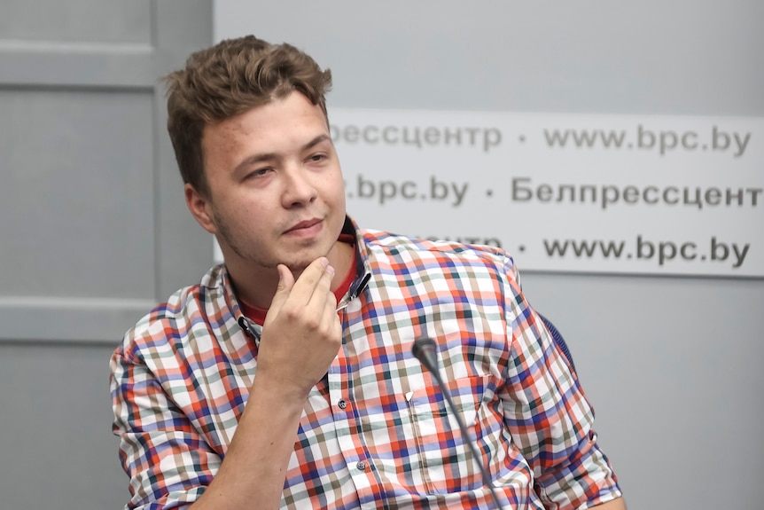 A waist-up photo of Jailed Belarus journalist Roman Protasevich takes part in a press conference.