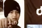 A still showing the boy posing with a gun during the video