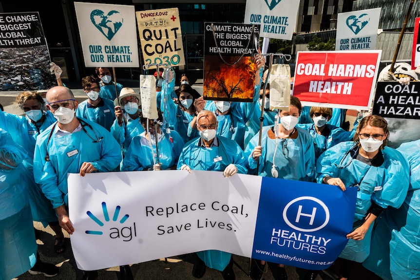 A group of people dressed in medical gowns holding a banner