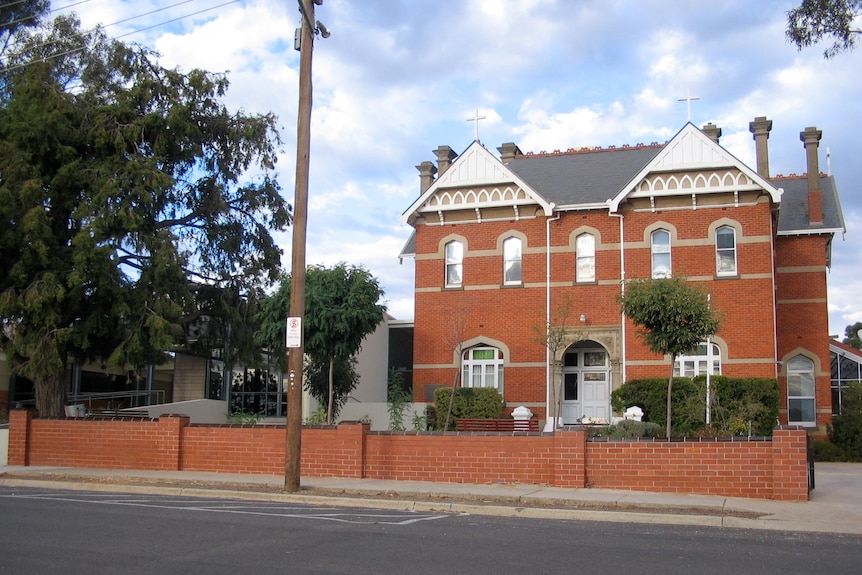 A large red brick building with a low brick fence out the front.