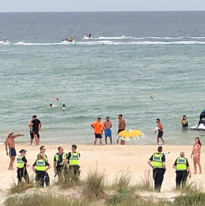 Police in high-visibility vests are pictured among beachgoers at Chelsea beach.