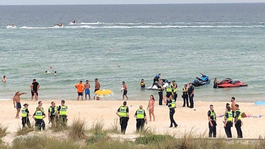 Police in high-visibility vests are pictured among beachgoers at Chelsea beach.