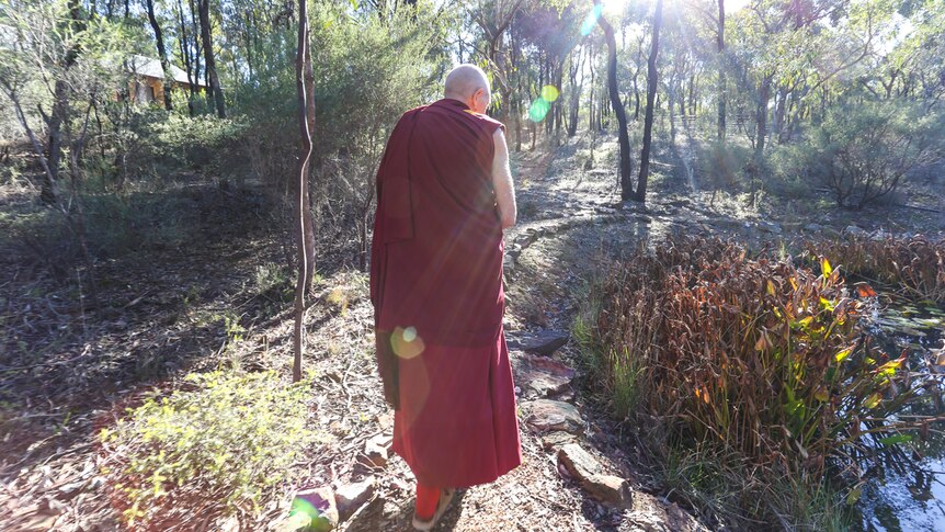Thubten  Gyatso walking up a path in the bushland of the monastery.