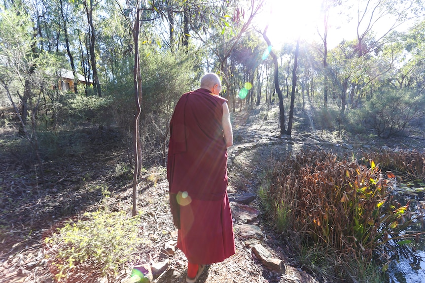 Thubten  Gyatso walking up a path in the bushland of the monastery.