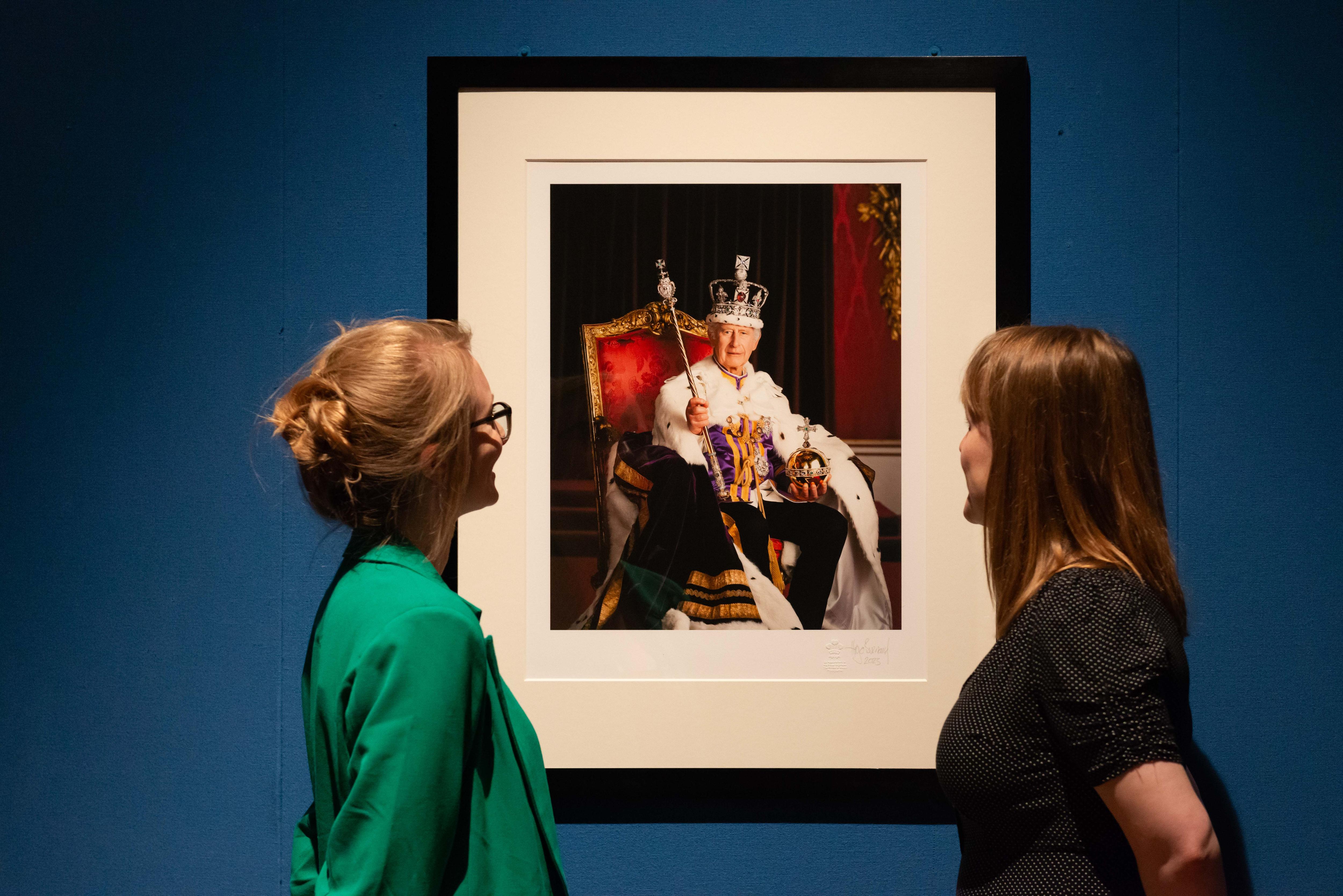 King Charles III's coronation photo hanging in the exhibition with two women looking at it