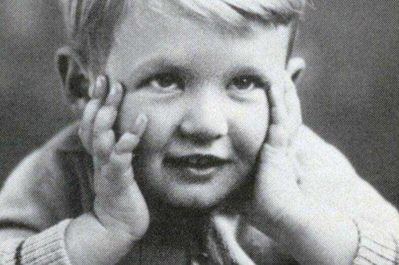 A black and white photo of a boy holding his chin in his hands