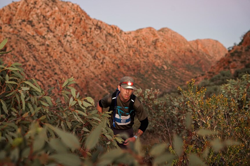 A trail runner with a mountain range behind him.