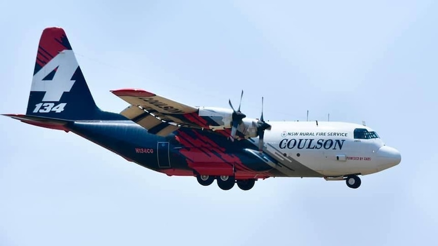 a large plane flying in the air with the nsw rural fire service symbol on the side