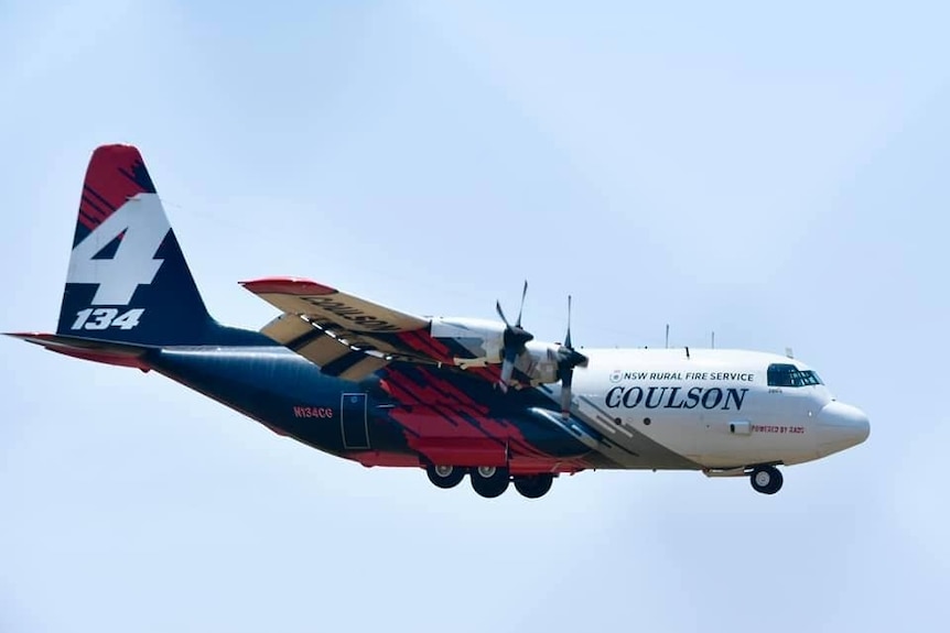 a large plane flying in the air with the nsw rural fire service symbol on the side