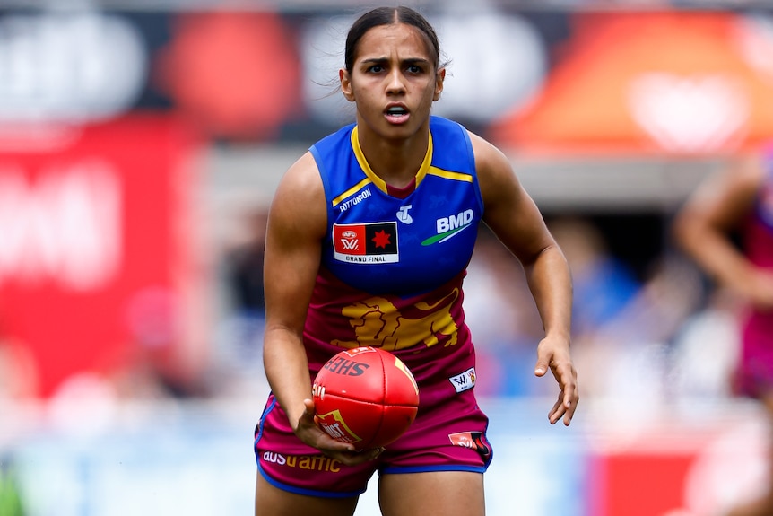 A Brsbane Lions AFLW player holds the ball during the grand final.