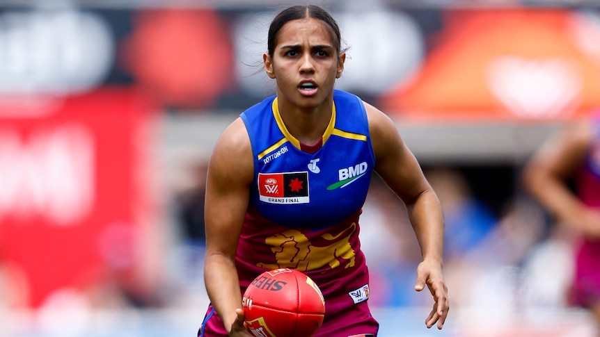 A Brsbane Lions AFLW player holds the ball during the grand final.