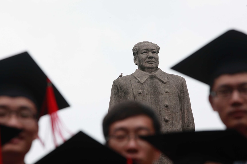 Fudan University graduates pose for a picture in front of the statue of late Chinese leader Mao Zedong.