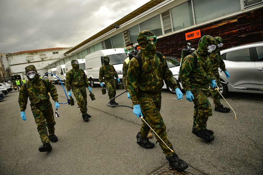 Member of Military Emergency Unit walk with special equipment to disinfect areas