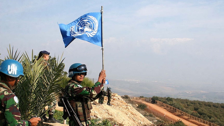 a united nations peacekeeping soldier waves a UN flag