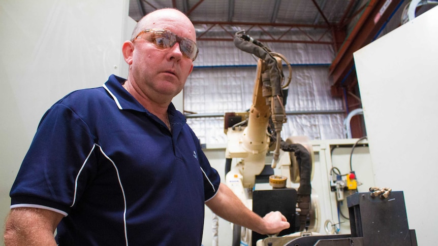 Harley Hollier with a robot working arm at his workshop in West Kalgoorlie.