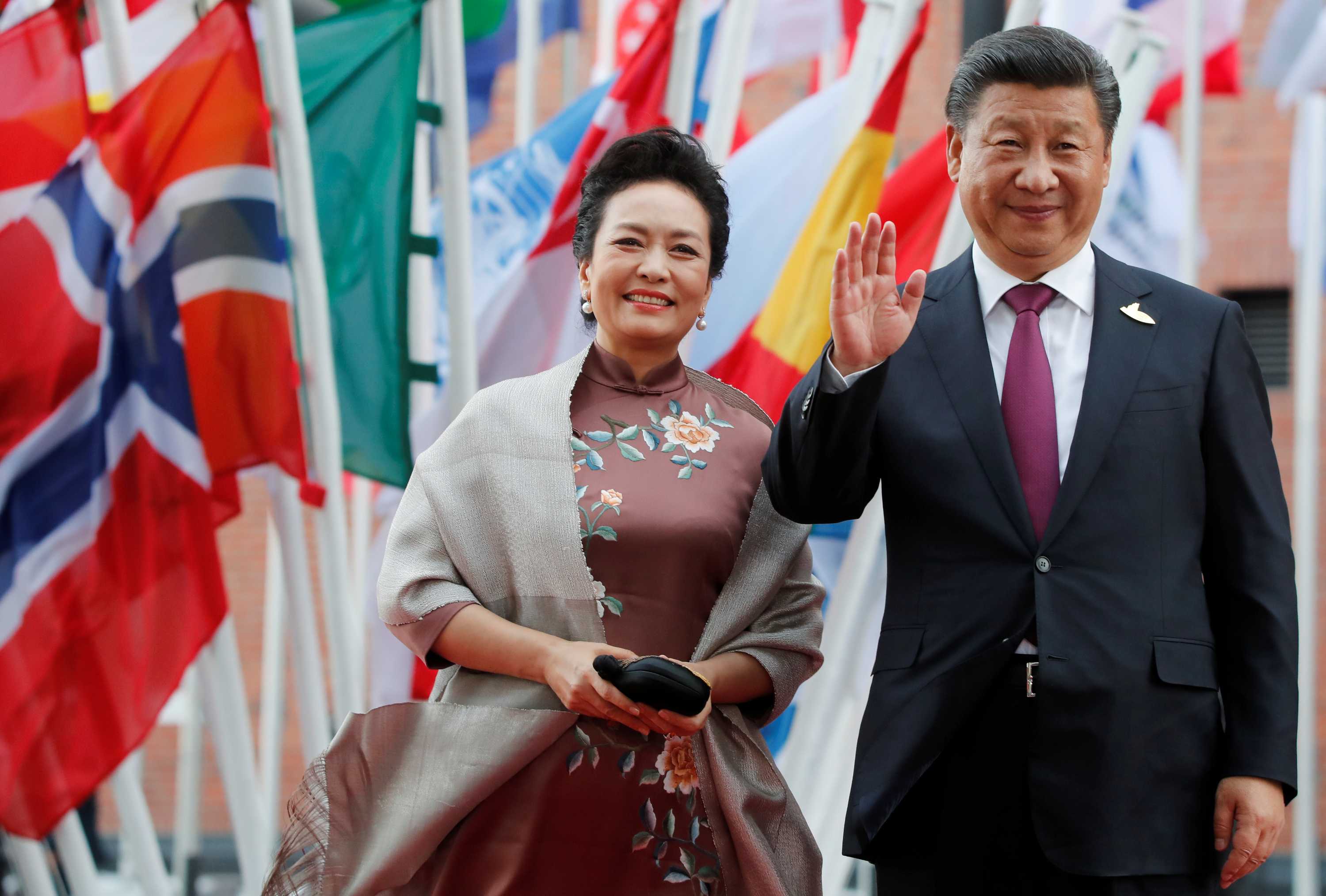 Peng Liyuan, left, and Xi Jinping, right, stand in front of international flags.