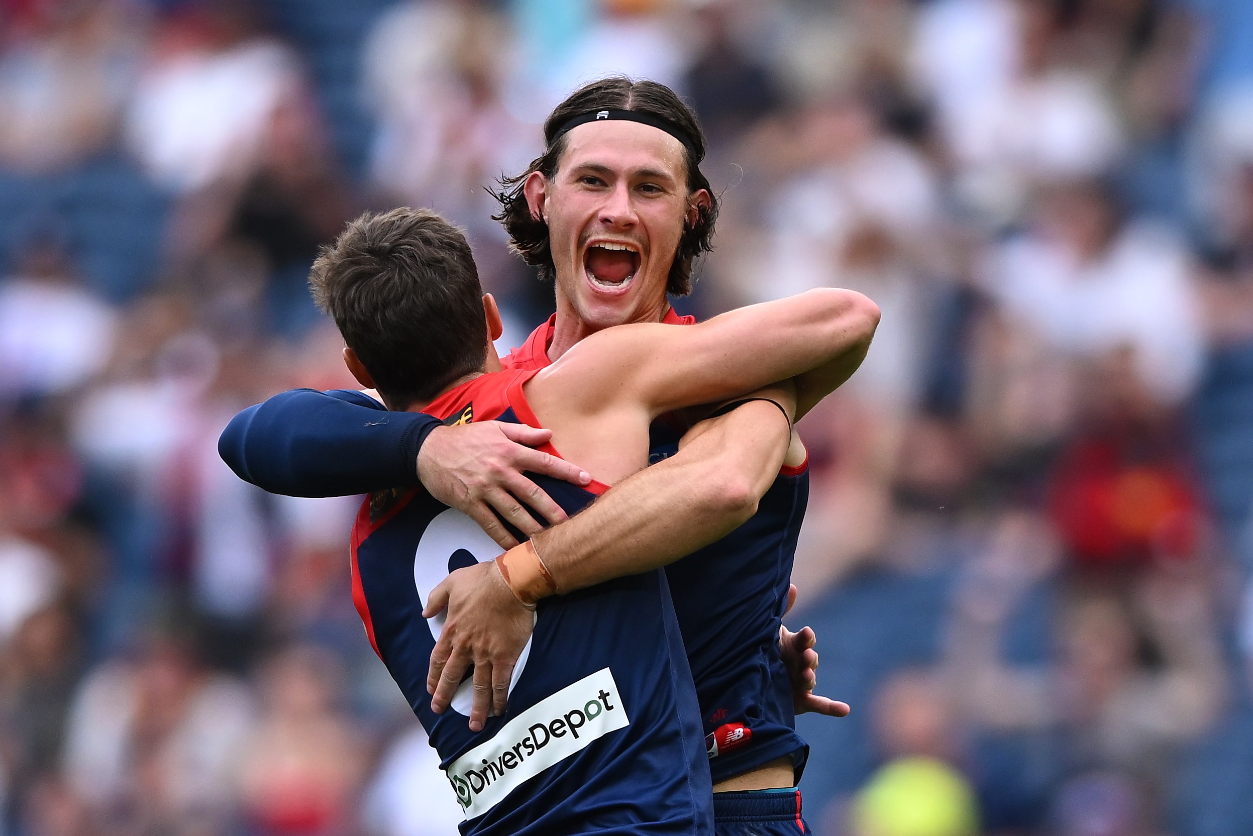 Dois jogadores do Melbourne AFL se abraçam ao comemorar um gol contra o St Kilda.