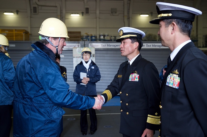 Christopher Pyne shakes hands with a defence force official in Japan.