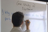 Teacher writes on a whiteboard