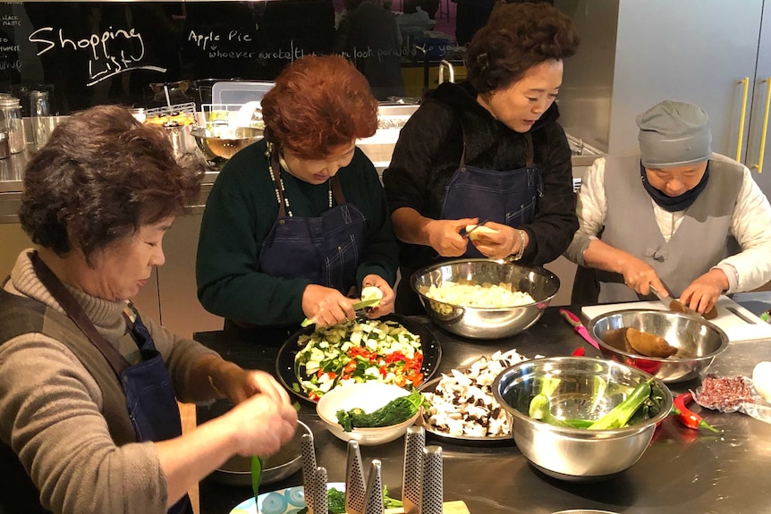 Middle-aged Asian ladies chopping up vegetables in the kitchen