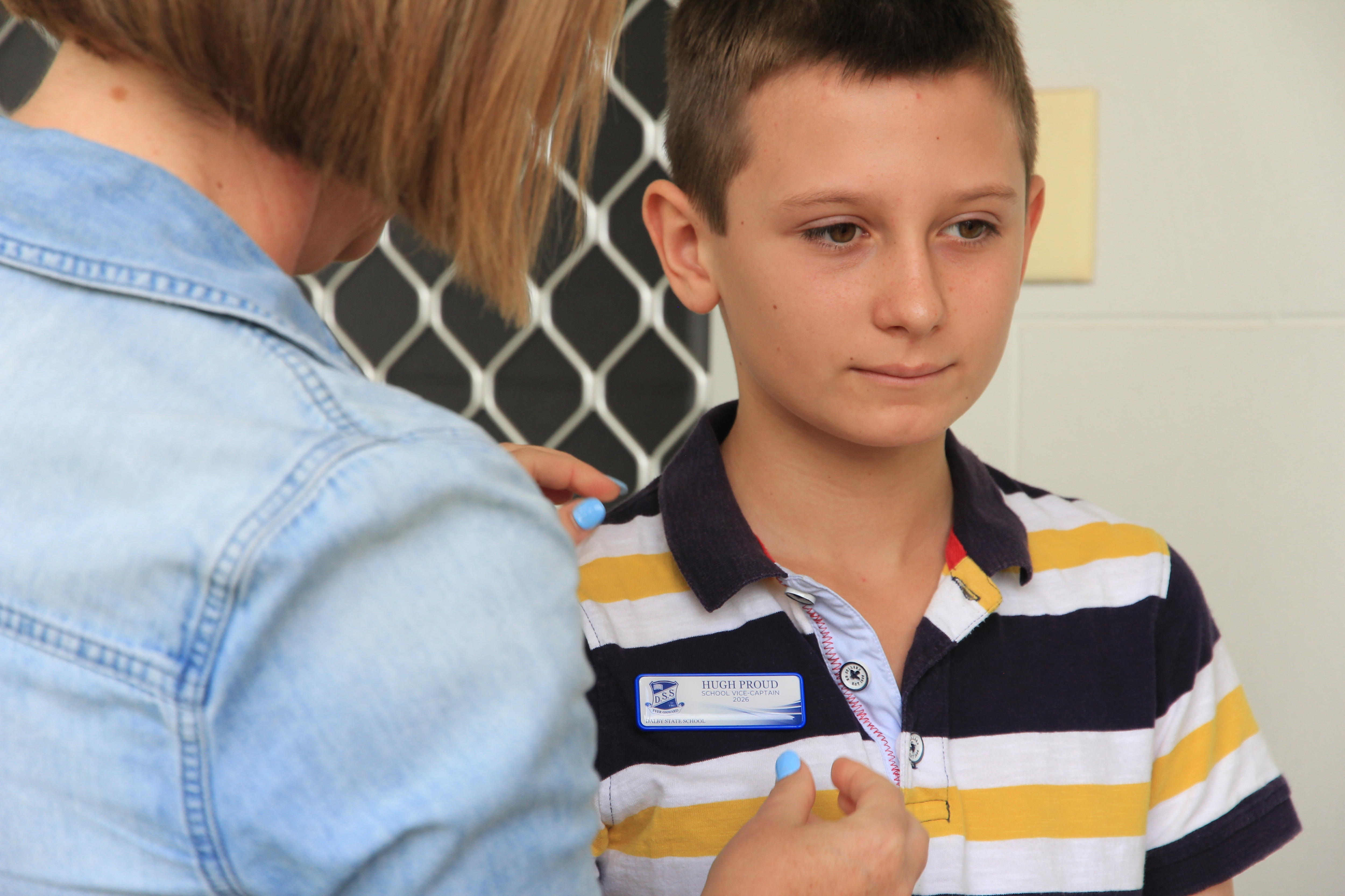 La madre de Hugh coloca una insignia de vicecapitán en la camisa de Hugh. 