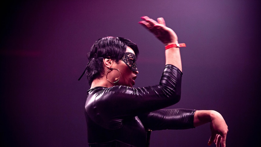 Colour photo of participant on stage in front of judges at Sissy Ball 2019, wearing a catwoman suit.