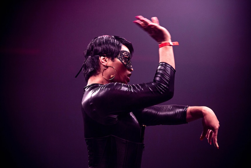 Colour photo of participant on stage in front of judges at Sissy Ball 2019, wearing a catwoman suit.