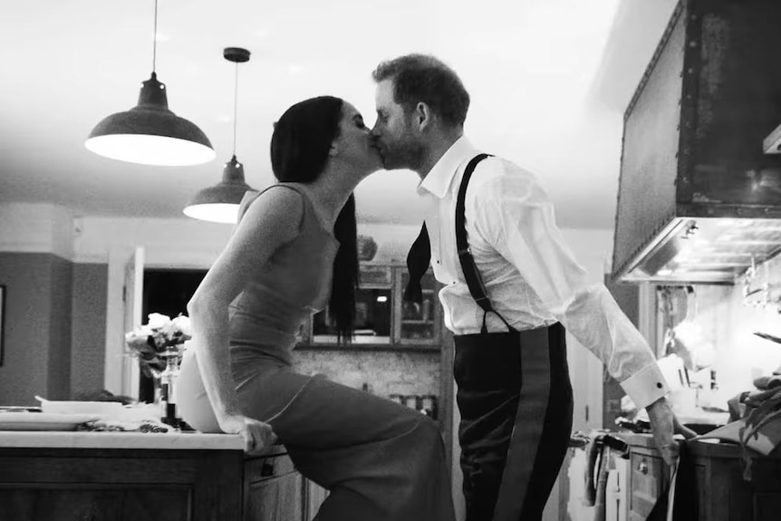 A black and white photo of Harry and Meghan kissing in a kitchen