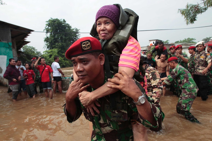 A soldier carries a woman after she was evacuated from her flooded house in Kampung Pulau in Jakarta.