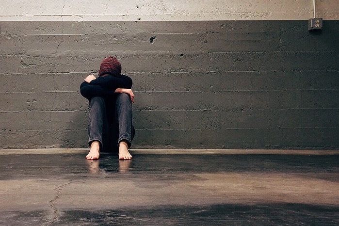 Depressed young person sitting alone in causeway.