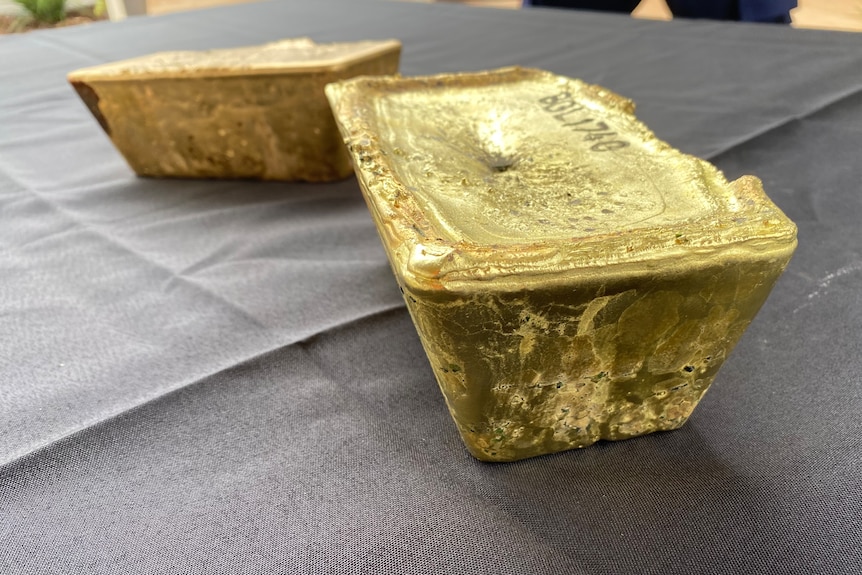 Two large gold bars on a black tablecloth