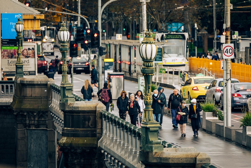 Pedestrians walk across Princes Bridge, viewed from the southern side of the Yarra River on a wet winter day.