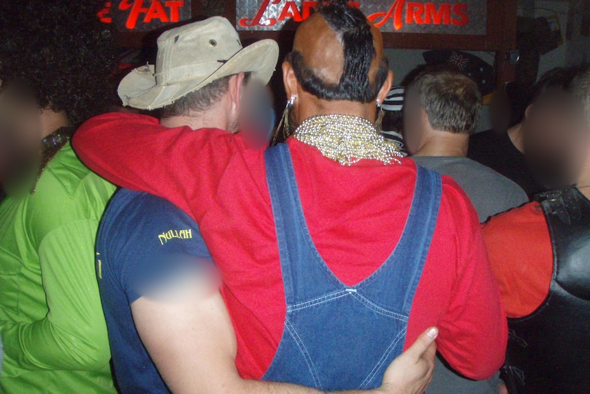 Two men embrace, one is a white man dressed as Mr T, with brownface makeup on.