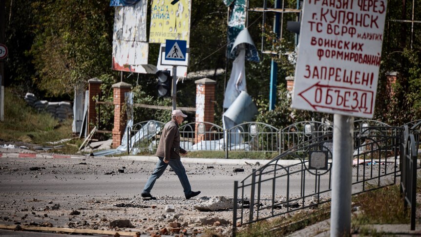 A man walks along a damaged street in the town of Kupiansk.