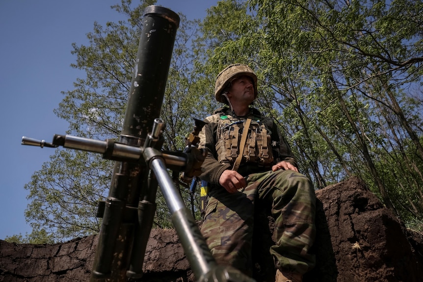 Ukrainian service member prepares to fire a mortar.