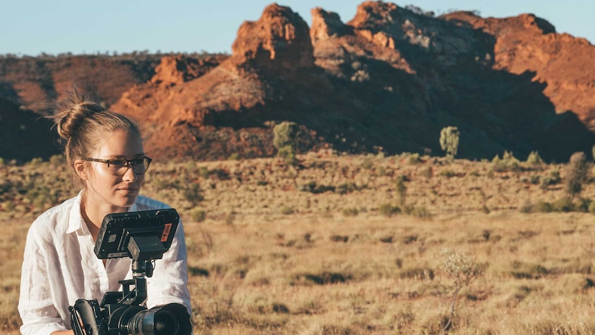 Young woman shooting on a camera in the outback desert