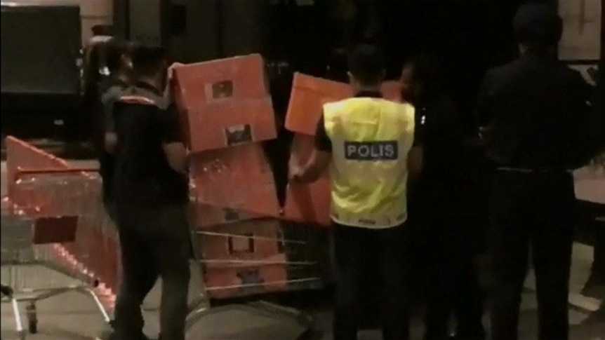 Police remove suitcases full of goods from one of the family's properties