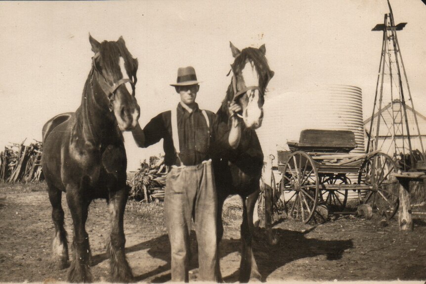 A historic photo of a man working his land with two horses.
