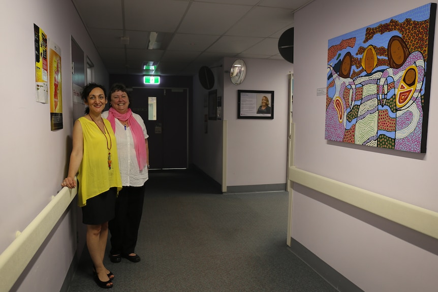 Laurel Rogers and Ellie Saberi in hospital corridor with Aboriginal artwork on the wall