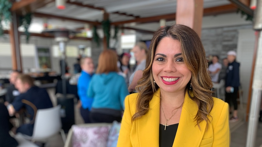 A woman with a yellow jacket smiles.