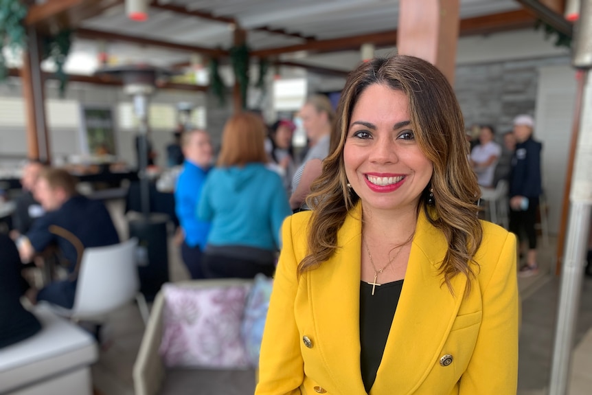 A woman with a yellow jacket smiles.