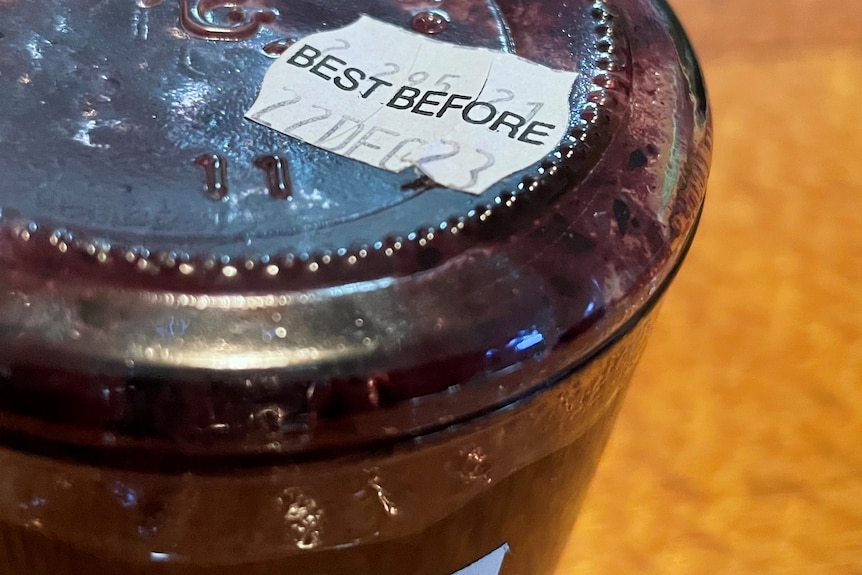 A best before sticker on the bottom of a jar of presevered blueberries. 