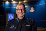 Commander Glenn Weir smiling while standing in room at Victoria Police office.